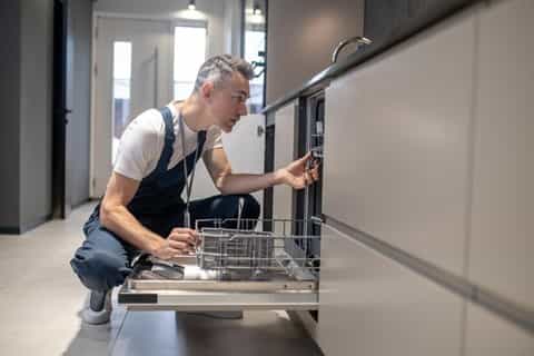 a man looking into dishwasher